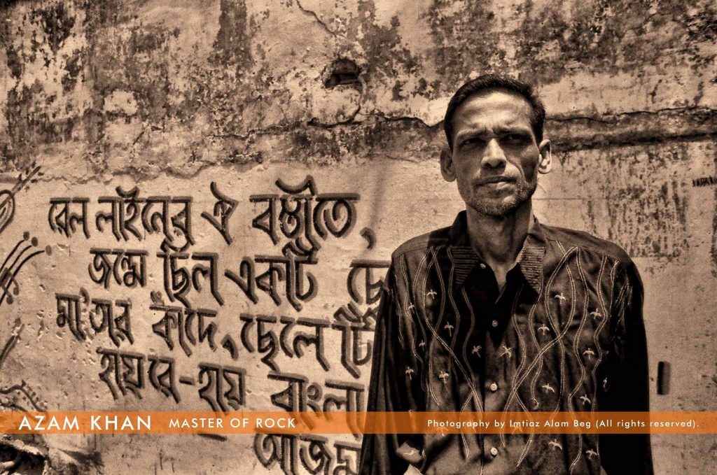 আজম খানের পেছনে দেয়ালে লেখা তাঁর বিখ্যাত গান ‘বাংলাদেশ’ এর কয়েকটি লাইন